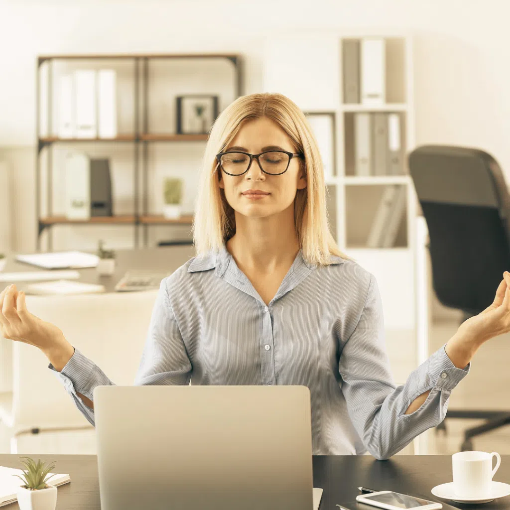 Mujer meditando en oficina con ordenador portátil