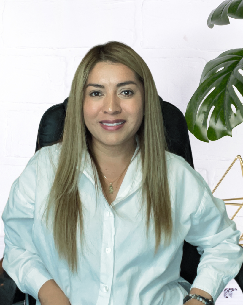 Mujer sonriente en oficina con planta de fondo.